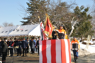 晴天の下、消防団旗の入場により開式