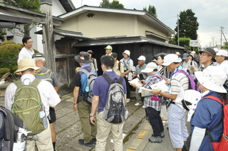 黒板塀の邸宅前で講師が説明